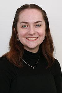 woman with dark shoulder length hair wearing a black turtle neck swearter